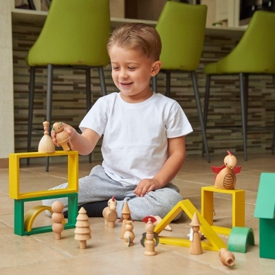 Criança a brincar com brinquedos de madeira coloridos no chão