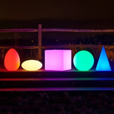 Luminárias coloridas em formas geométricas variadas, iluminadas à noite