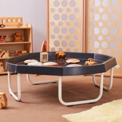 Mesa octogonal baixa com brinquedos de madeira num ambiente infantil