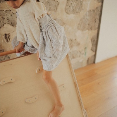 Criança a subir em parede de escalada de madeira em ambiente interior