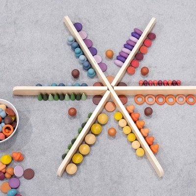 Peças de madeira coloridas organizadas em estrela com recipiente branco ao lado