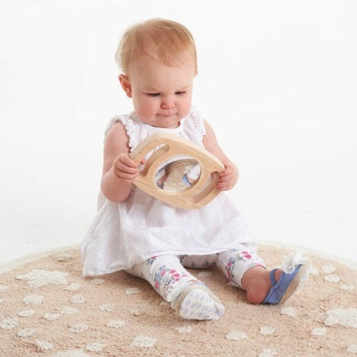 Bebé sentado no chão a brincar com brinquedo de madeira e espelho num tapete redondo