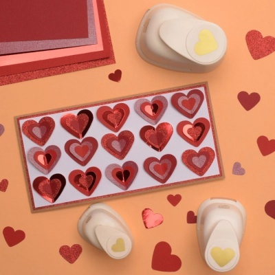 Furadores de papel e recortes em forma de coração em tons de vermelho e rosa