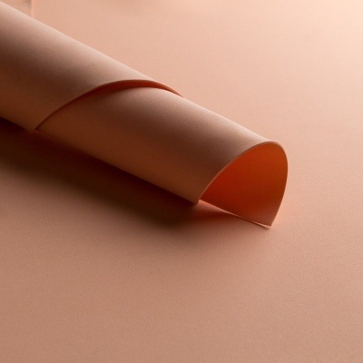 Folha de papel rosa claro enrolada sobre superfície rosa