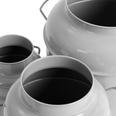 Três jarros de metal branco com líquido escuro no interior e alças finas em fundo branco