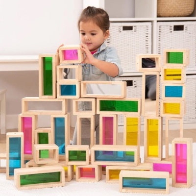 Blocos de construção em madeira com painéis coloridos translúcidos e criança a brincar