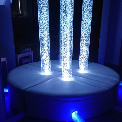 Três colunas de bolhas iluminadas em base redonda branca com luz azul