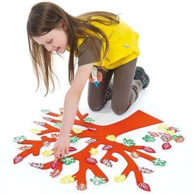 Criança a brincar com árvore educativa vermelha e folhas coloridas