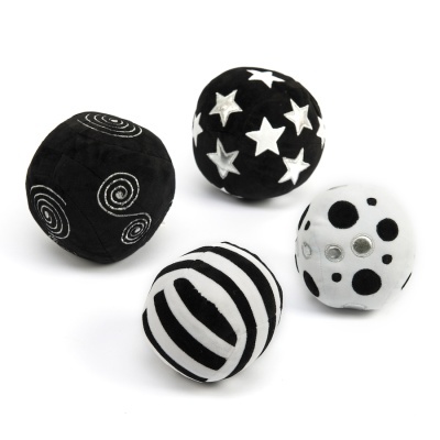 Quatro bolas de brinquedo têxteis em preto e branco com padrões distintos