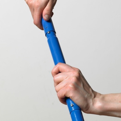 Duas mãos seguram tubo azul com parafusos metálicos num fundo cinzento claro.