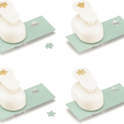 Quatro perfuradores de papel branco com diferentes padrões em papel verde