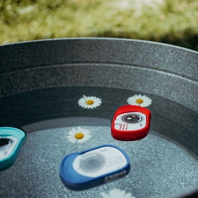 Três câmaras de ação flutuantes em balde metálico com água e flores brancas.