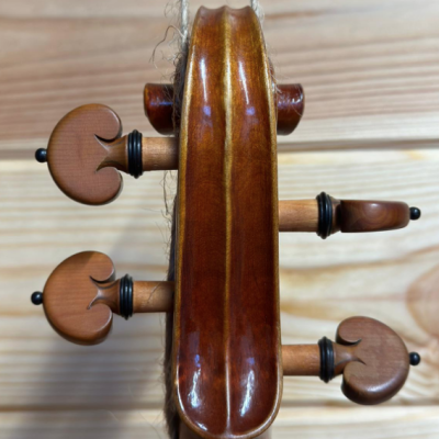 Topo do braço de violino em madeira polida com cravelhas e fundo de madeira clara