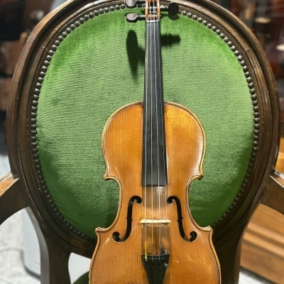 Violino de madeira clara numa cadeira estofada verde com braços de madeira