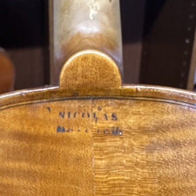 Parte traseira de um violino em madeira com texto azul 'NICOLO IS MADE IN ITALY'
