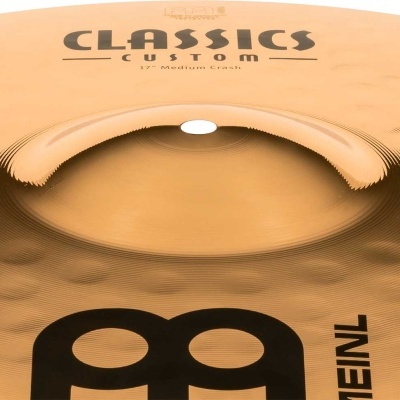 Prato de bateria dourado com texto 'CLASSICS CUSTOM 17'' Medium Crash' e logo 'MEINL'