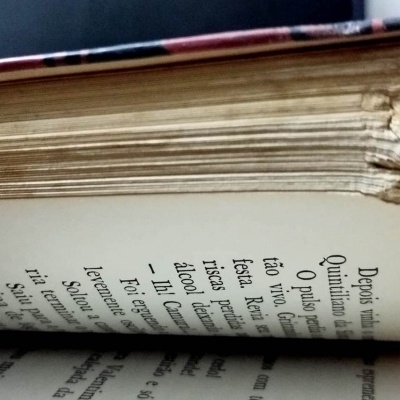 Livro antigo com páginas danificadas e texto em português