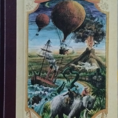 Livro com capa ilustrada mostrando balões, navio, serpente marinha, elefante e vulcão.