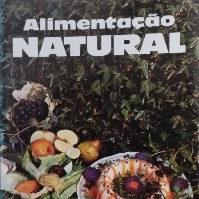 Capa de livro 'Alimentação NATURAL' com frutas, vegetais e prato decorado sobre folhagem verde