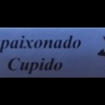Fita azul com texto 'Apaixonado Cupido' e símbolos em preto e branco ao lado, e edifício histórico à esquerda