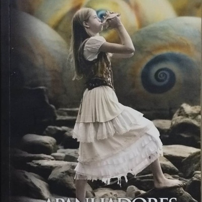 Capa do livro Os Apanhadores de Conchas com jovem a soprar numa concha