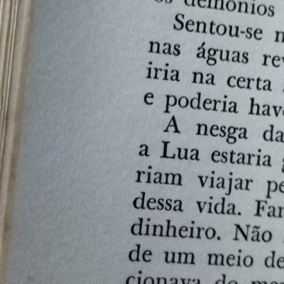 Página de livro com texto em português e canto rasgado