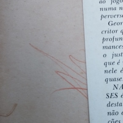 Pormenor de página de livro português com manchas e lápis de cor laranja