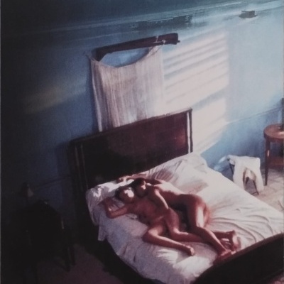 Livro O Amante de Marguerite Duras com casal nu na cama e decoração simples