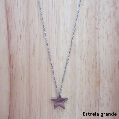 Colar com pendente estrela roxa em corrente prateada sobre madeira clara