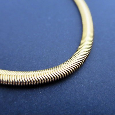 Colar dourado de escamas em fundo azul escuro