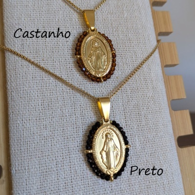 Colares dourados com pendentes ovais e pedras castanhas e pretas em suporte de tecido beije