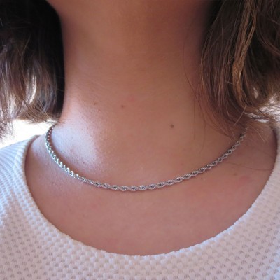 Colar de corrente fina em prata num pescoço com t-shirt branca texturizada