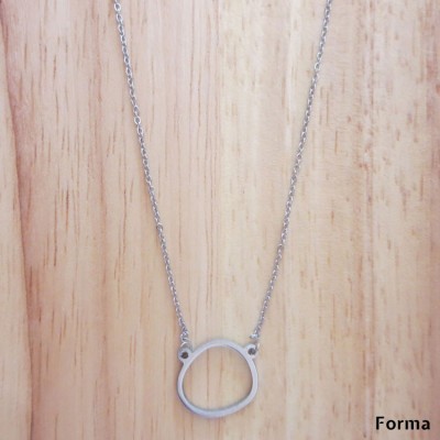 Colar prateado com pendente circular irregular sobre fundo de madeira clara