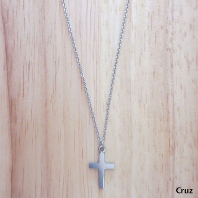 Colar prateado com pendente em forma de cruz sobre fundo de madeira clara