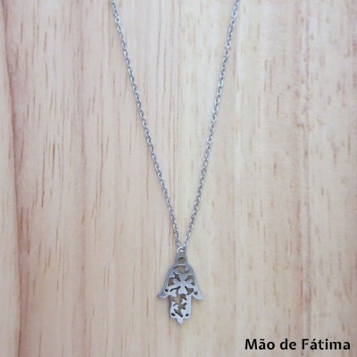 Colar com pendente Mão de Fátima em metal prateado sobre fundo de madeira