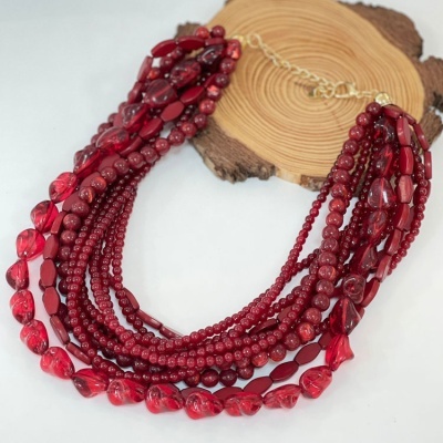 Colar múltiplas voltas com contas vermelhas variadas sobre base de madeira circular