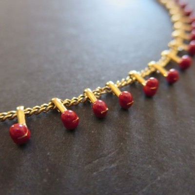 Colar dourado com pendentes vermelhos em forma de maçãs