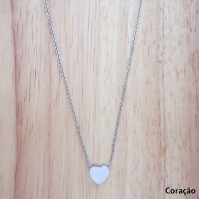 Colar prateado com pendente em forma de coração sobre fundo de madeira clara