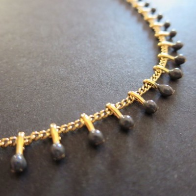 Colar dourado com pendentes pretos em superfície preta