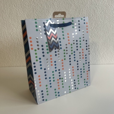 Saco de presente em papel com pontos coloridos e etiqueta pendurada