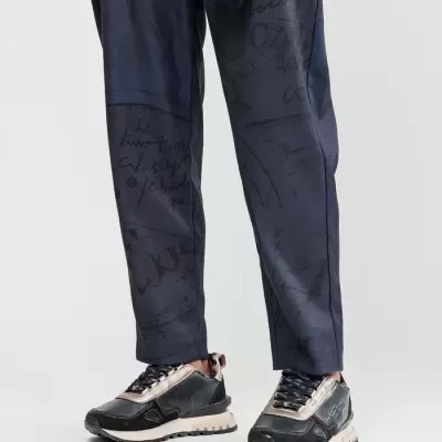 Calças azuis escuras com padrão de escrita e ténis preto com detalhes bronze e branco