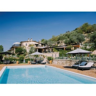 Piscina exterior com espreguiçadeiras e casa de pedra ao fundo