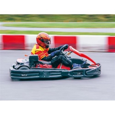 Carrinho de karting preto e vermelho numa pista com barreira vermelha e branca