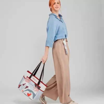 Mulher com camisa azul e calças largas bege segurando mala estampada