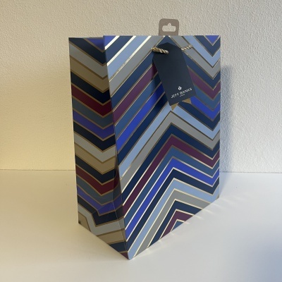 Saco de presente de papel com padrão geométrico colorido e etiqueta 'Happy Xmas'