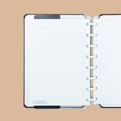 Caderno inteligente aberto com páginas brancas e capa preta sobre fundo bege.