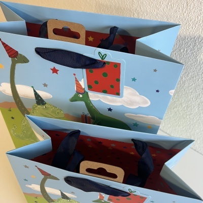 Sacolas azuis ilustradas com dinossauros e chapéus de festa