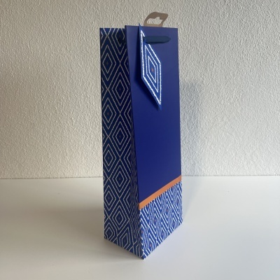 Saco de papel azul com padrão geométrico branco e detalhes em laranja