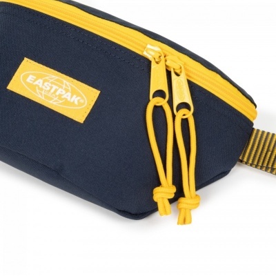 Mala de cintura Eastpak azul escuro com fecho amarelo e etiqueta amarela da marca