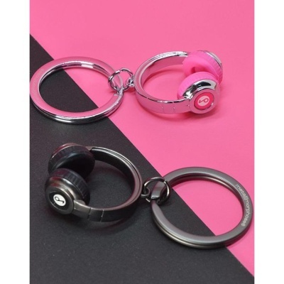 Porta-chaves em forma de auscultadores prateado com rosa e preto sobre fundo rosa e preto